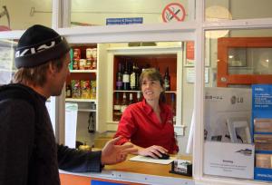 a woman talking to a man at a counter at Elterwater Hostel in Elterwater
