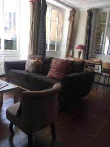 uma sala de estar com um sofá, cadeiras e janelas em le bal d'arsène em Aurillac