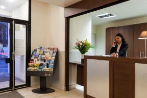 a woman talking on a phone at a reception desk at Annemasse Apparts in Annemasse