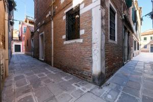 un callejón con un edificio de ladrillo y una ventana en La Perla, en Venecia