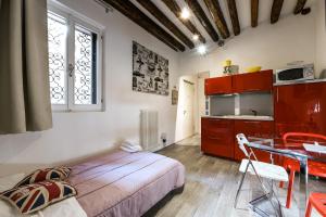 1 dormitorio con cama, mesa y cocina en La Perla, en Venecia