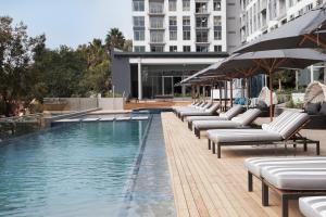 a swimming pool with lounge chairs and a building at The Capital on the Park in Johannesburg