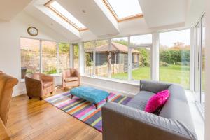 a living room with a couch and chairs and windows at Swiss Cottage in Aldringham