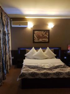 1 dormitorio con 1 cama grande con almohadas blancas en Casa Teilor, en Piteşti