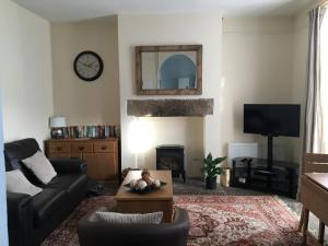 a living room with a couch and a clock on the wall at Twenty Seven Steps in Hebden Bridge