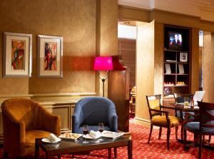 una sala de espera con sillas, mesas y una lámpara en Grand Hotel Gosforth Park, en Newcastle