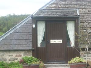 uma casa com uma porta castanha com um sinal em Parkmore Holiday Cottages em Dufftown