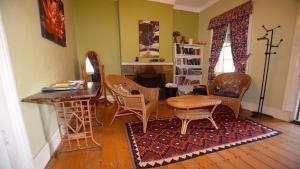 sala de estar con sillas, mesa y chimenea en Waragil Cottage - Original Settler's Home, en Blackheath