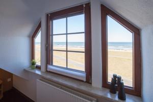 een kamer met 2 ramen met uitzicht op het strand bij Hotel Strandräuber in Kalifornien