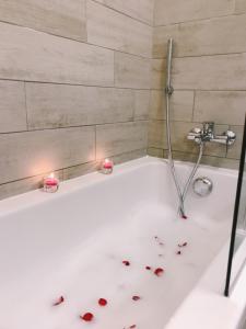 a bath tub with some rose petals on it at Hôtel Le Dauphin in Menton