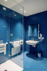 a blue bathroom with a sink and a shower at Air Rooms Rome Airport by HelloSky in Fiumicino