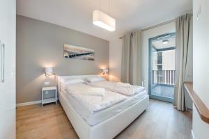 a white bed in a room with a window at Nadmorze, Sun & Snow in Gdańsk
