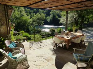 a patio with a table and chairs and a view of a river at Moulin de Latreille in Calès