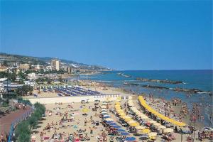 una spiaggia piena di persone con ombrelloni di Ristorante Albergo Roma ad Arma di Taggia