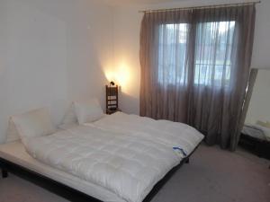 duże białe łóżko w pokoju z oknem w obiekcie Haus Gaschür w mieście Bad Ragaz