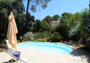 a swimming pool with an umbrella and a chair at Andre in Porto-Vecchio