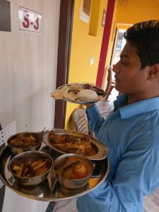 Een man houdt een dienblad met eten vast. bij Asian Grand Villa in Bolpur