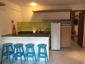 una cocina con cuatro taburetes azules frente a un mostrador en Flat no La Piazzetta - Ap. 14 Térreo, en Pipa