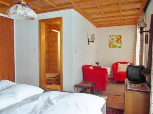 a bedroom with a bed and two red chairs at Pension Stüttler in Schruns