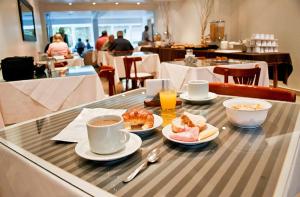 een tafel met borden en kopjes koffie bij Hotel Ortegal in Mar del Plata