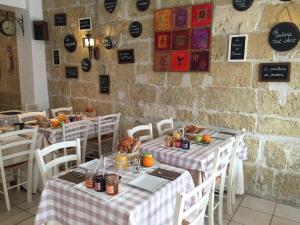 a restaurant with tables and chairs and a brick wall at Hôtel Restaurant Le Provençal in Le Grau-du-Roi