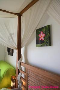 a bedroom with a canopy bed with a pink flower on the wall at Frangipani Studio Réunion in La Saline les Bains