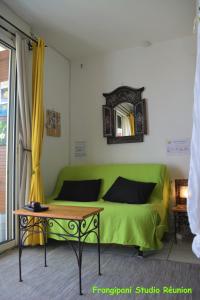 a living room with a green couch and a table at Frangipani Studio Réunion in La Saline les Bains