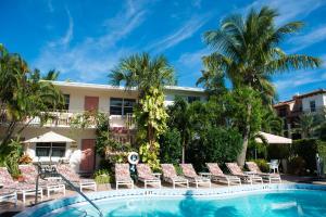a resort with a swimming pool with lounge chairs and palm trees at Shore Haven Resort Inn in Fort Lauderdale