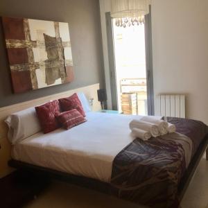 Un dormitorio con una cama con almohadas rojas y una ventana en Barcelona Bs Sitges, en Sitges