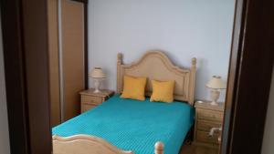 a bedroom with a bed with blue sheets and yellow pillows at Casa Largo dos Cedros in Nazaré