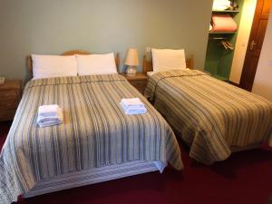 two beds in a hotel room with towels on them at Pier House Bed & Breakfast in Inis Mor