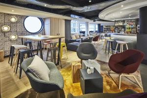 a restaurant with chairs and tables and a bar at Radisson Hotel Paris Le Bourget in Le Bourget