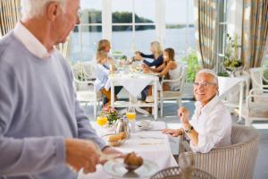 Strauers Hotel am See في Bosau: رجل وامرأة كبيران في السن يجلسان على طاولة في مطعم