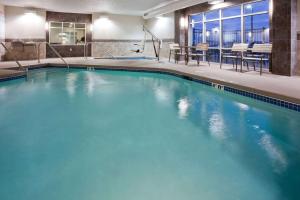 a large pool with blue water in a hotel room at AmericInn by Wyndham Waupun in Waupun