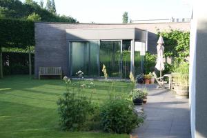 d'un jardin avec une maison en verre et une pelouse. dans l'établissement La Chambre d'Amis, à Ypres