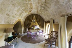 sala de estar con mesa, sillas y pared de piedra en Masseria Celano en Grottaglie