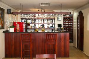 a bar with two stools and a counter with alcohol at Hotel Los Jardines in Santiago de los Caballeros