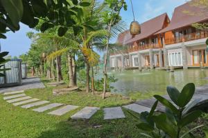 eine Reihe von Häusern und ein Teich mit Palmen in der Unterkunft Grand Mega Resort & Spa in Cepu