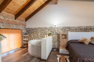 a bedroom with a bed and a bath tub next to a stone wall at Estudio Sonido y Jacuzzi in Santander
