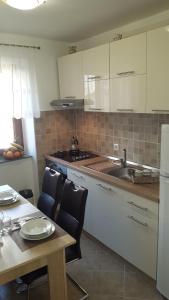 una cocina con armarios blancos y una mesa con sillas. en Paradise apartment - Old town Rab en Rab