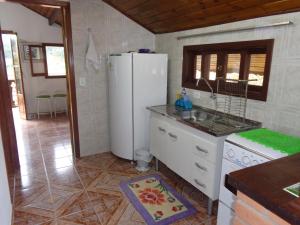 a kitchen with a white refrigerator and a sink at Recanto Monte Verde in Monte Verde