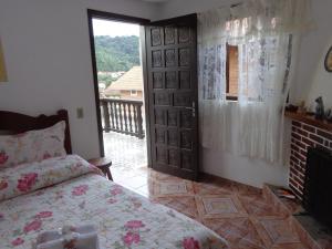 a bedroom with a bed and a fireplace and a window at Recanto Monte Verde in Monte Verde
