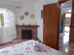 a bedroom with a fireplace and a bed with shoes on it at Recanto Monte Verde in Monte Verde