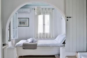 アギオス・イオアニス・ミコノスにあるVilla Athena by Elite Estatesのベッドルーム1室(窓のあるアーチ型のベッド1台付)