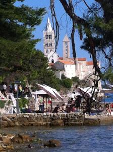 un gruppo di persone sedute su una spiaggia con una chiesa di Paradise apartment - Old town Rab a Rab