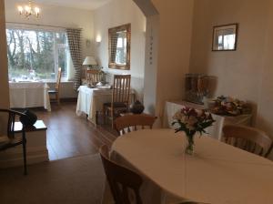a dining room with a table with a vase of flowers on it at Bron Aber in Criccieth