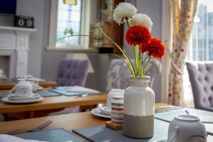 um vaso com flores vermelhas e brancas sobre uma mesa em The Beechcliffe Hotel - Over 35's Only em Blackpool