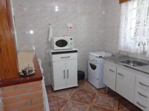 a small kitchen with a microwave and a sink at Recanto Monte Verde in Monte Verde