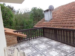 a balcony with a table and chairs and a roof at Recanto Monte Verde in Monte Verde
