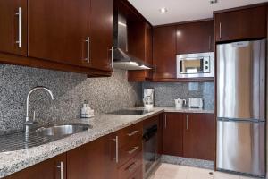 a kitchen with wooden cabinets and a stainless steel refrigerator at OFFLINE - Altos in Torremolinos